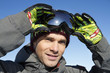 Young man looking at camera, removing his ski goggles