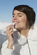 Young woman applying lip balm