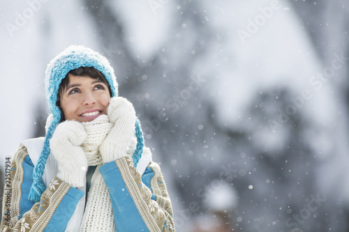 Foto: Young woman in winter clothes looking up Young woman in winter clothes looking up