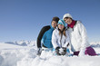 Couple and daughter in ski wear sitting in snow