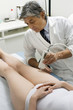 woman receiving laser treatment at the leg from a male doctor