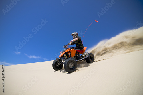 Photo: Big sand spray from ATV quadbike rider in the dunes Big sand spray from ATV quadbike rider in the dunes