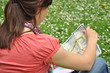 adventure girl with a map of the city siting on the grass