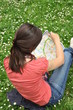 adventure girl with a map of the city siting on the grass