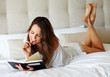 Sexy young female reading book on bed