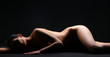 Beautiful naked body of a brunette on a dark background