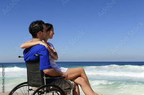 Photo: woman and husband in wheelchair on the beach woman and husband in wheelchair on the beach