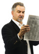 Mature man reads newspaper with serious look on face Mature man reads newspaper with serious look on face