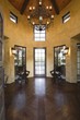 Wood floored vestibule with candelabra hanging from high ceiling