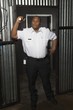 Security guard stands at corrugated metal doorway with torch