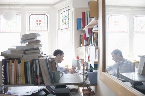 Photo: mid adult man working in cluttered study mid adult man working in cluttered study