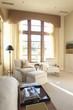 Sunlit floor to ceiling windows in cream living room interior