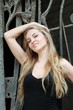 Young attractive blond girl near the park fence
