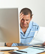 Worried Man with Headache Paying Bills