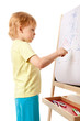 Four-year old boy drawing picture on easel