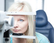 optometry concept - pretty young woman having her eyes examined