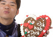 Asiatischer Mann hält Oktoberfest Herz und gibt Luftkuss