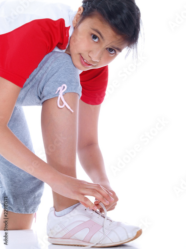 Photo: young girl tying her sports shoes isolated on white background young girl tying her sports shoes isolated on white background