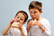 two boys eating sandwiches