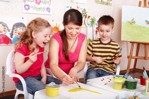 Foto: Children with teacher draw paints in play room. Children with teacher draw paints in play room.