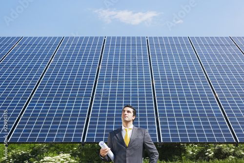 Photo: businessman standing near solar panels businessman standing near solar panels