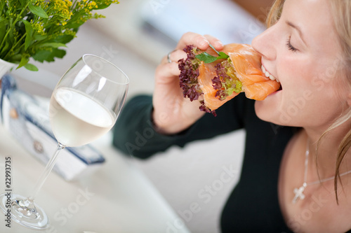 Foto: junge frau beißt in frisches lachsbrötchen junge frau beißt in frisches lachsbrötchen