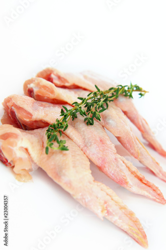 Photo: raw chicken wings with thyme on white background raw chicken wings with thyme on white background