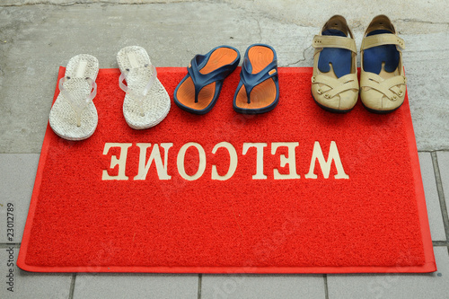 Photo: Pairs Of Shoes At A Red Welcome Mat