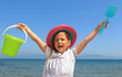 Pretty young girl holding a bucket and spade abover her head