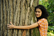 Photo: In love with nature: woman hugging a tree in the forest In love with nature: woman hugging a tree in the forest