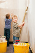 Zwei Kinder malern eine Wand daheim Zwei Kinder malern eine Wand daheim