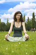 Photo: Young woman meditating in a park Young woman meditating in a park
