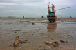 Fishing boat stuck on shore with an anchor