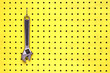 One adjustable wrench hangs from a hook on yellow pegboard One adjustable wrench hangs from a hook on yellow pegboard