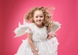 Beautiful little angel girl isolated on pink background