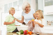 Grandchildren Helping Grandmother To Prepare Salad In Kitchen