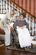 Senior woman in wheelchair with nurse helping