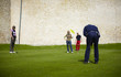 Man putting on the green with group of golfers watching