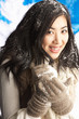Young Woman Wearing Warm Winter Clothes Holding Snowball In Stud