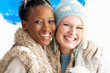 Two Young Women Wearing Warm Winter Clothes Holding Snowball In