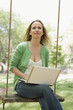 Foto: Woman Using Laptop on a Swing Woman Using Laptop on a Swing
