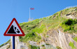 'Beware falling rocks' sign with steep cliffs in the background