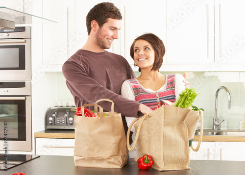 Photo: Young Couple Unpacking Shopping In Modern Kitchen Young Couple Unpacking Shopping In Modern Kitchen