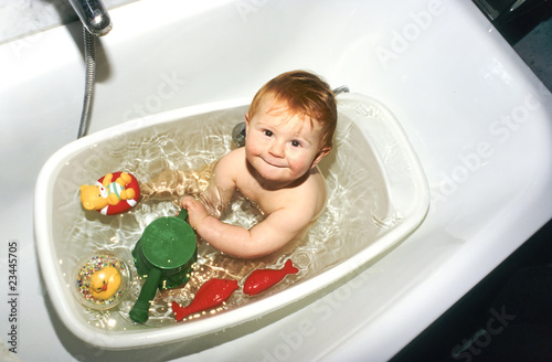 Photo: Baby planscht in seiner Babybadewanne mit Plastikspielzeug Baby planscht in seiner Babybadewanne mit Plastikspielzeug