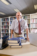 Photo: Portrait of mature man at library table with textbooks Portrait of mature man at library table with textbooks
