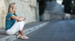 Very pretty young woman sitting on the sidewalk.