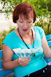 The elderly woman sits in park in hands of money The elderly woman sits in park in hands of money