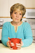 Senior woman, looking unhappy, holds a coffee mug Senior woman, looking unhappy, holds a coffee mug