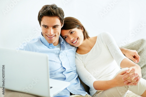 Photo: Modern lifestyle - Happy young couple using laptop at home Modern lifestyle - Happy young couple using laptop at home