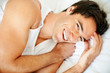 Cheerful young guy waking up in morning on bed